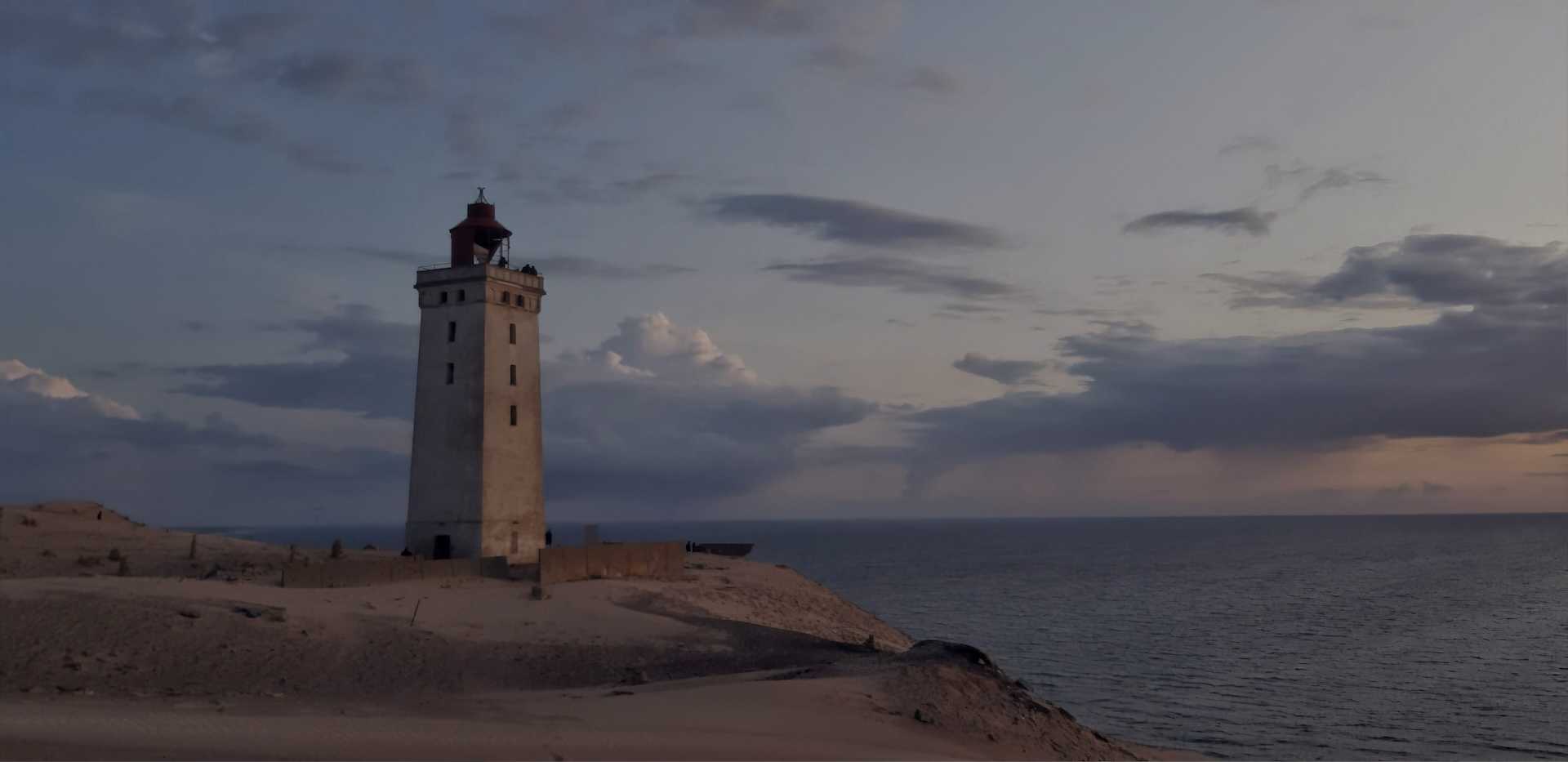 A lighthouse on a cliff overlooking the ocean